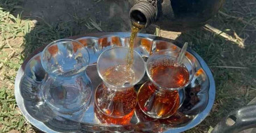 Yaz sıcaklarında çalışan Karacabeyli tarım işçileri, odun ateşinde demlenen çayla dinleniyor.