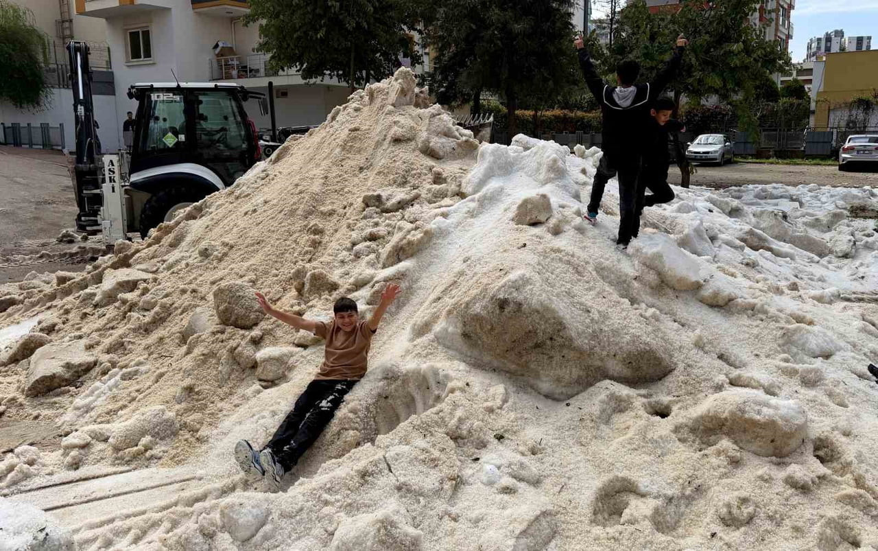 ADANA'DA DÜN ETKİLİ OLAN DOLU YAĞIŞININ ARDINDAN OLUŞAN VE ERİMEYEN BUZ KÜTLELERİNDE ÇOCUKLAR KAR...