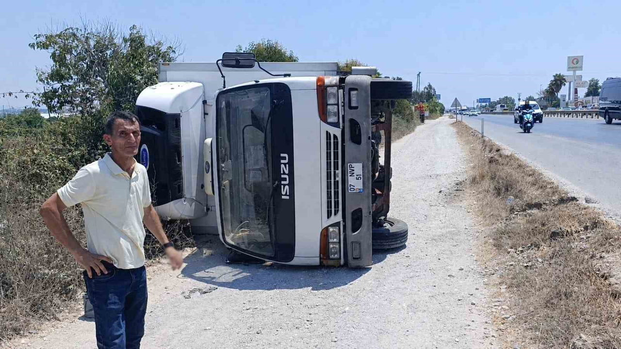 ANTALYA’NIN MANAVGAT İLÇESİNDE ŞARAMPOLE DEVRİLEN KAMYONUN SÜRÜCÜSÜ, YOLDAN GEÇEN VATANDAŞLARIN...