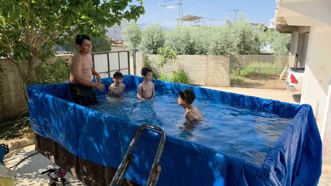 HATAY'DA HAVA SICAKLIĞININ 35 DERECEYİ BULMASIYLA SERİNLEMEK İSTEYEN TORUNLARININ EĞLENDİRMEK...