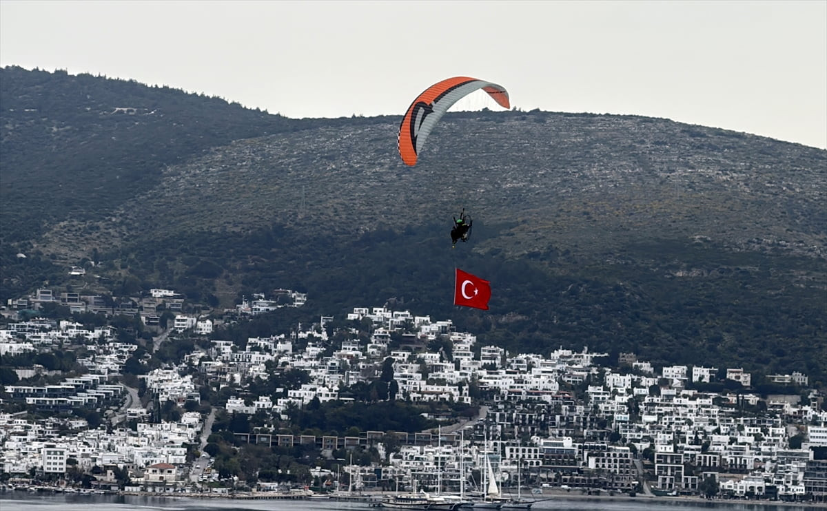 Muğla'nın Bodrum ilçesinde paramotoruyla uçarak dev Türk bayrağı açan pilot, şehitleri andı ve...