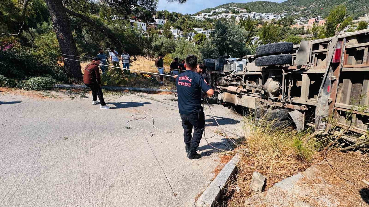MUĞLA’NIN BODRUM İLÇESİNDE İŞ MAKİNESİ TAŞIYAN KAMYONUN YOKUŞ ÇIKTIĞI SIRADA DEVRİLİRKEN, KAZADA...